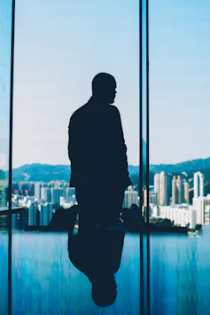 Silhouette of man looking out window at city skyline
