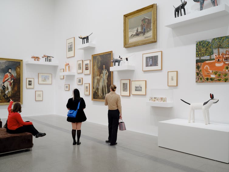 People in a gallery, looking at dogs.