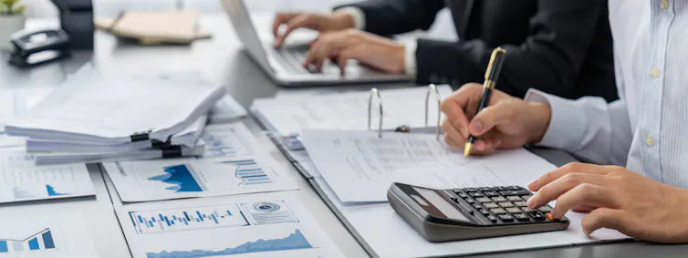 Auditor and accountant team work at table with calculators, financial documents
