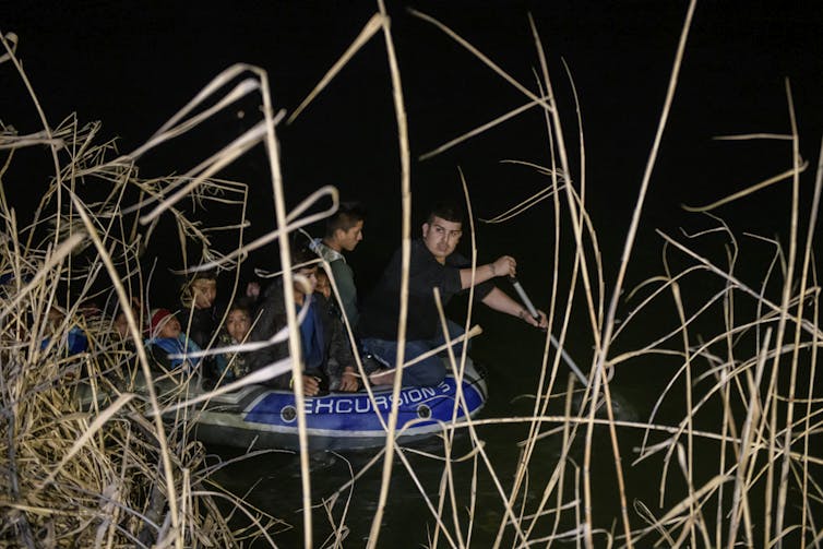 Nighttime shot of a man rowing an inflatable boat across a river