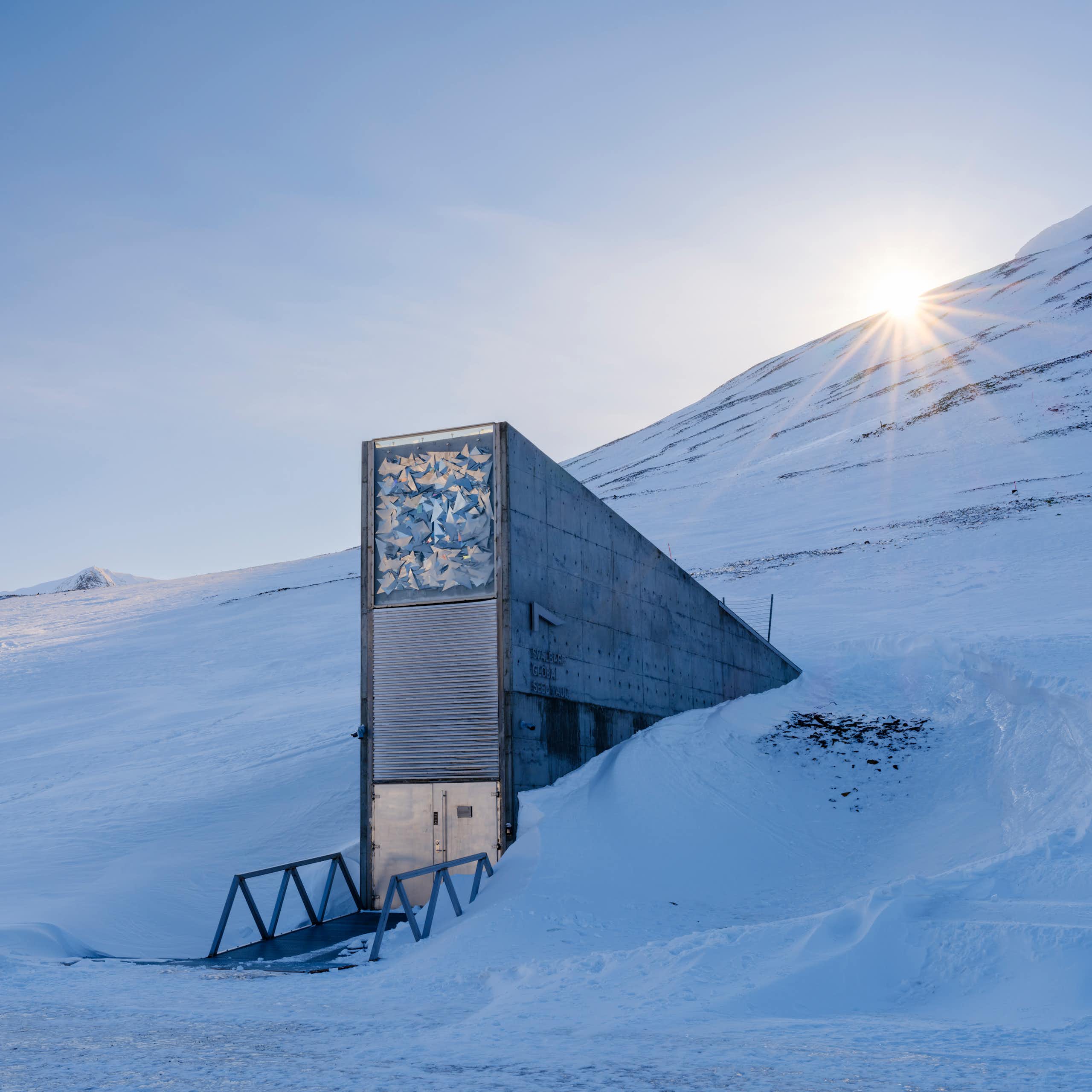 A rectangular shaft decorated with an artwork projects from a snowy hillside