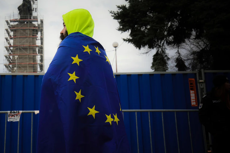 A man wrapped in a European flag looking into the distance.