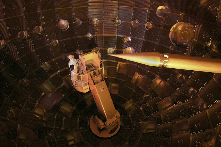 A metal chamber with a researcher wearing a hard hat inside.