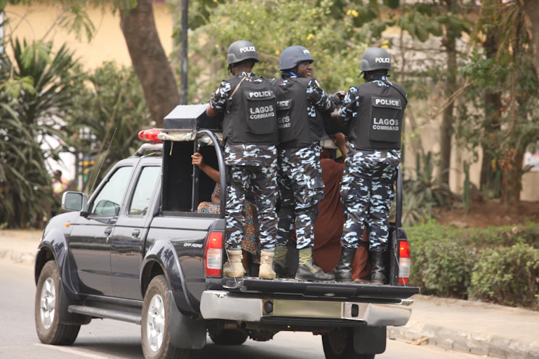 Men in police uniform hanging on the tail of van