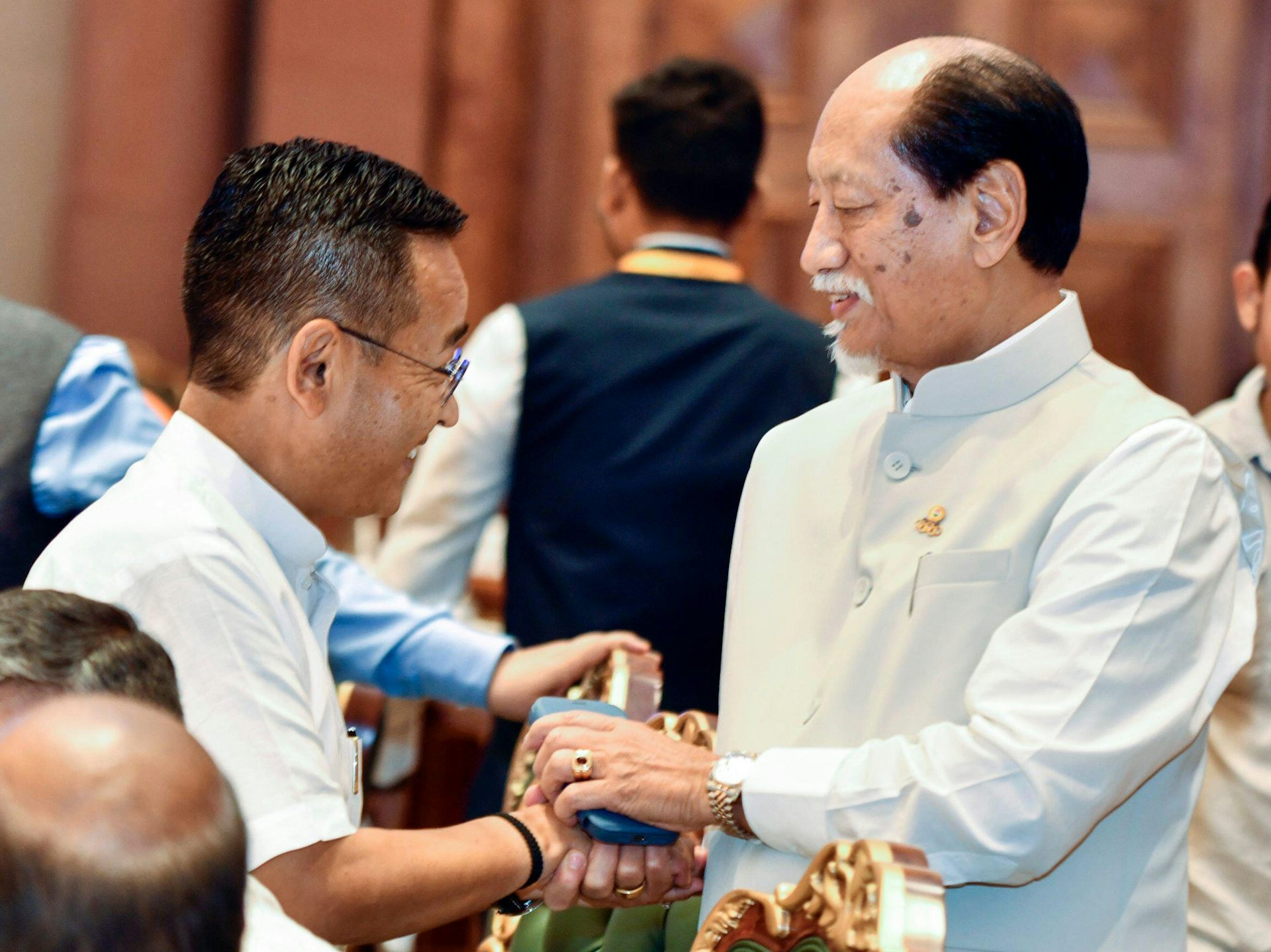 Neiphiu Rio apertando a mão de outro homem.