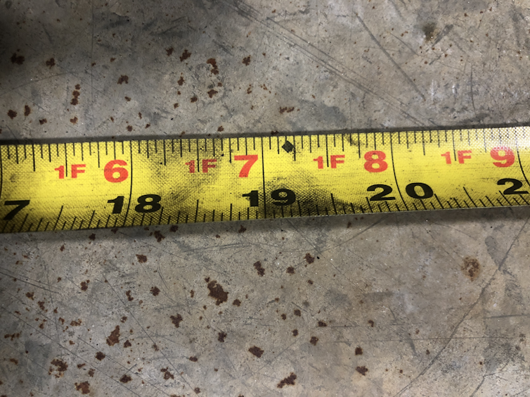 A yellow tape measure that shows a black diamond at 19 3/16 inches.