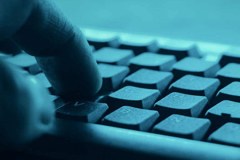 Fingers typing on a dimly lit keyboard