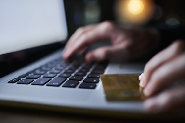 Closeup person holding credit card using laptop