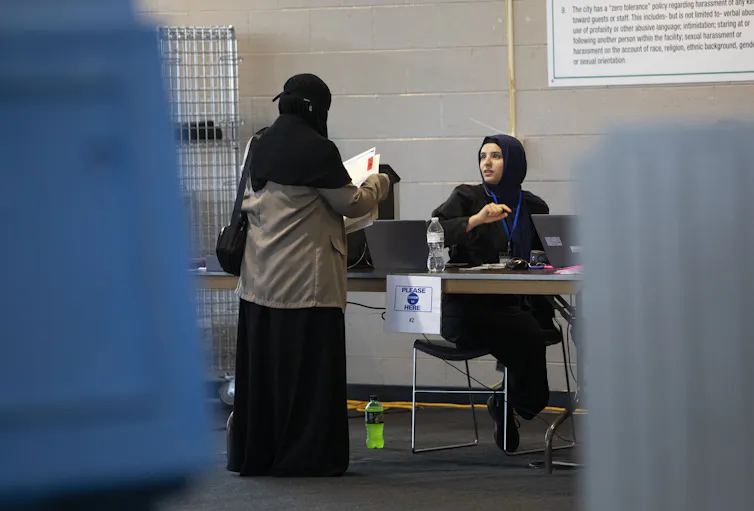 Two women in black veils cast their ballot papers for the election at the voting table