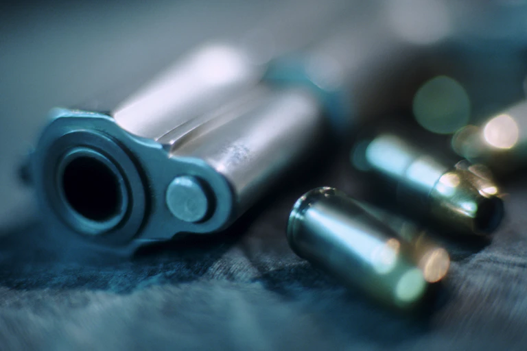 A blurry barrel of a handgun and bullets