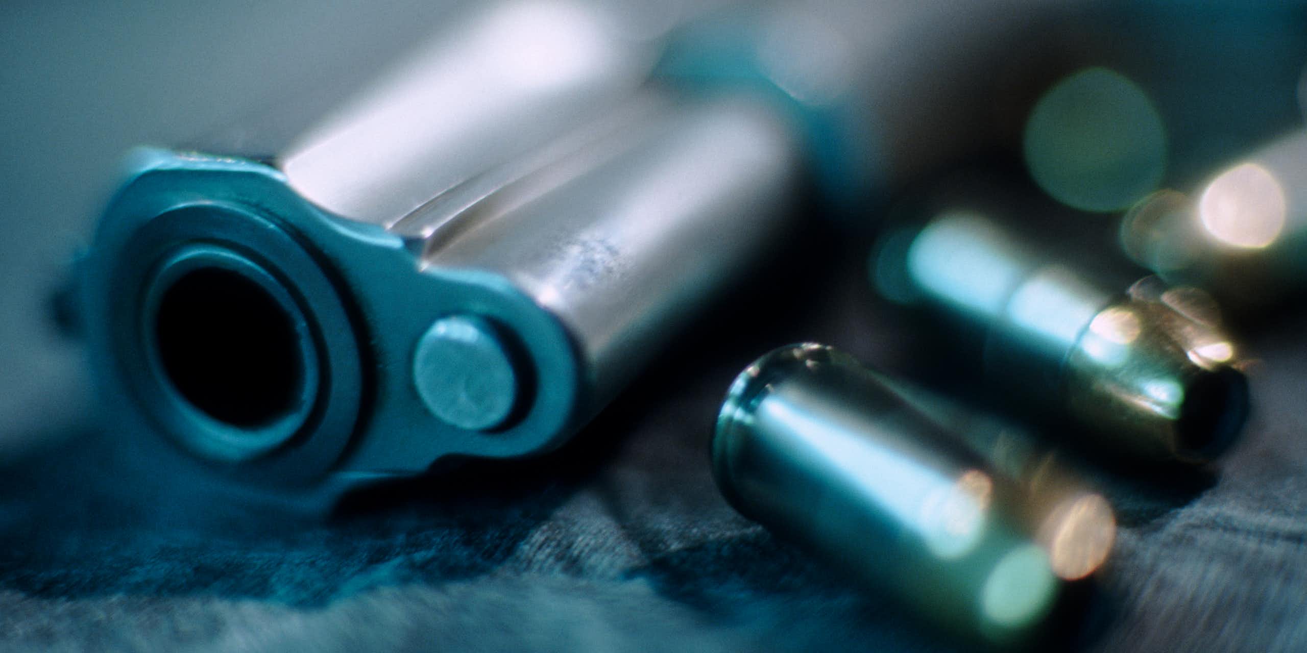 A blurry barrel of a handgun and bullets