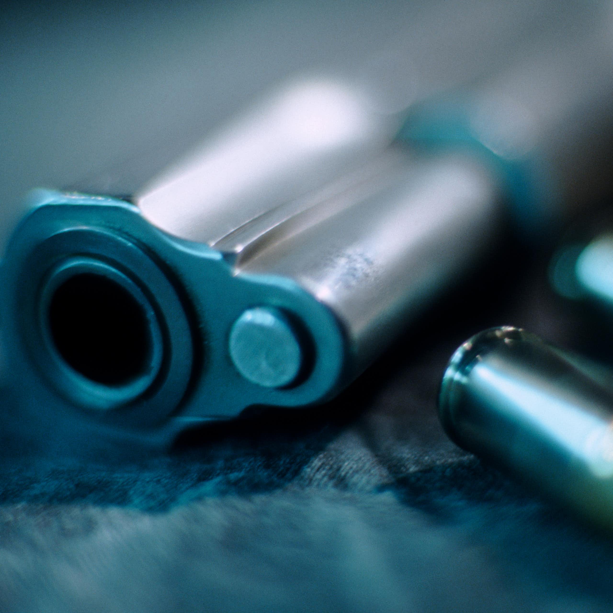 A blurry barrel of a handgun and bullets