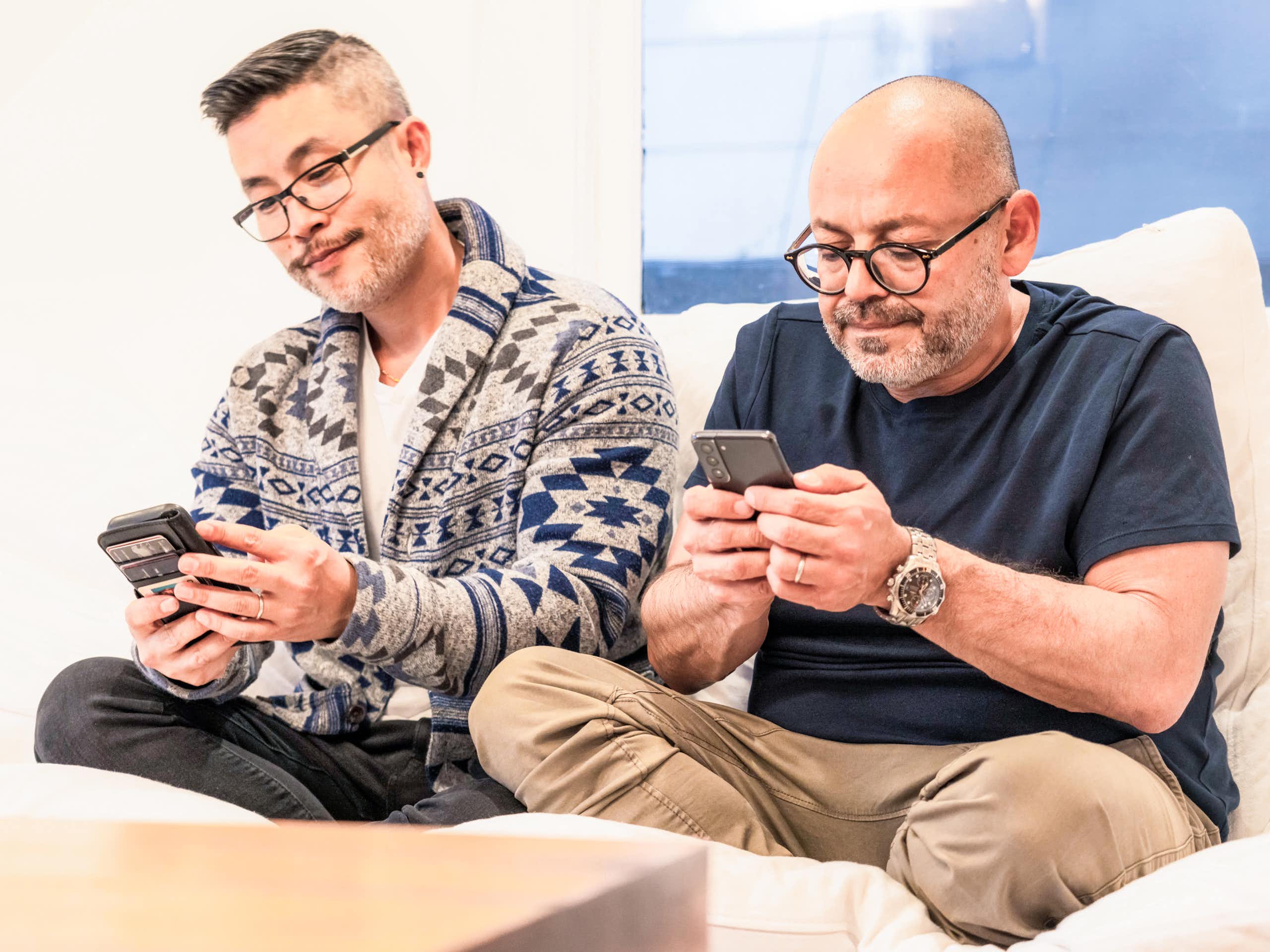 two seated men looking at phones with consternation