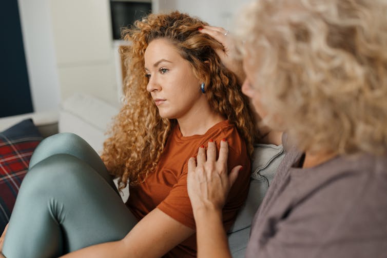 older woman comforts a younger woman who is looking off into distance
