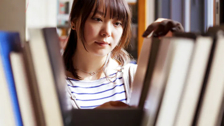 A young woman browsers shelves in a library.