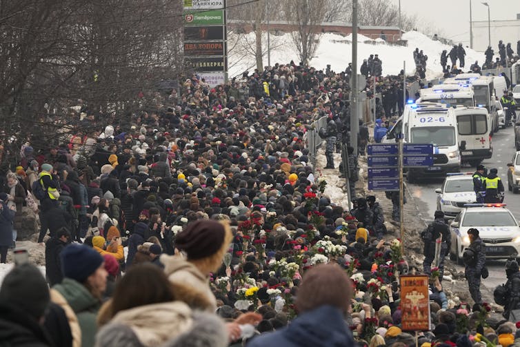 A crowd of people, in the snow, gather to mourn Navalny.