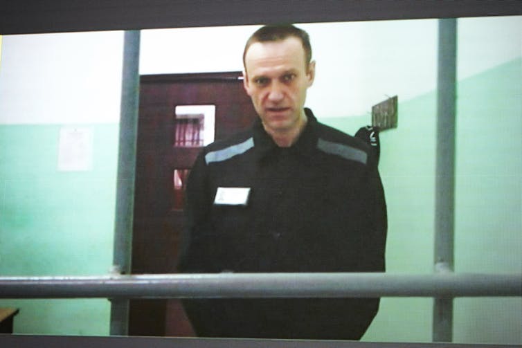 A man in prison uniform appears on video in court.