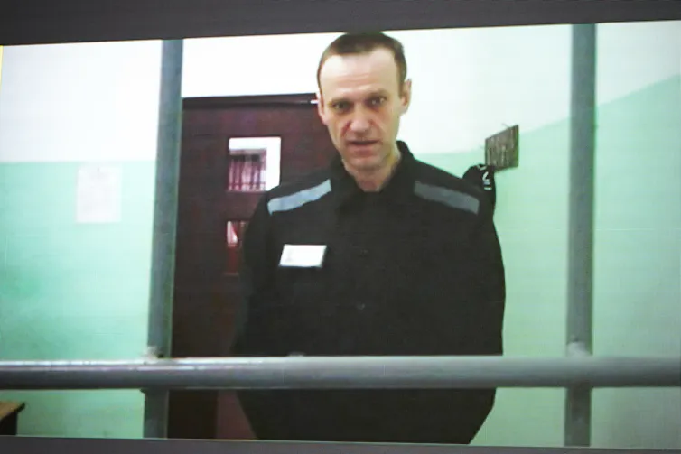 A man in prison uniform appears on video in court.