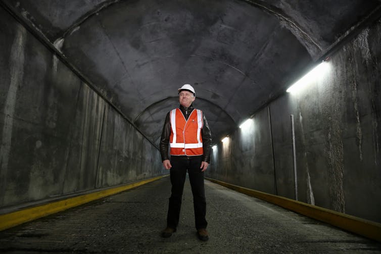 man in high-vis stands in tunnel