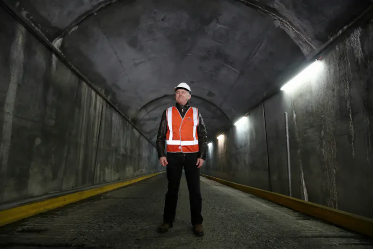 man in high-vis stands in tunnel