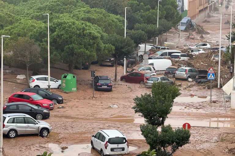 Coches situados caóticamente en una calle inundada de agua de color marrón