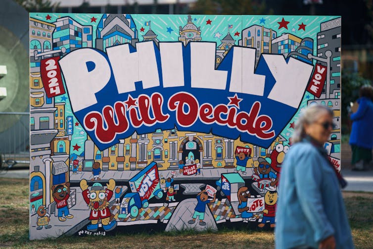 A woman passes signs encouraging early voting near Philadelphia City Hall.