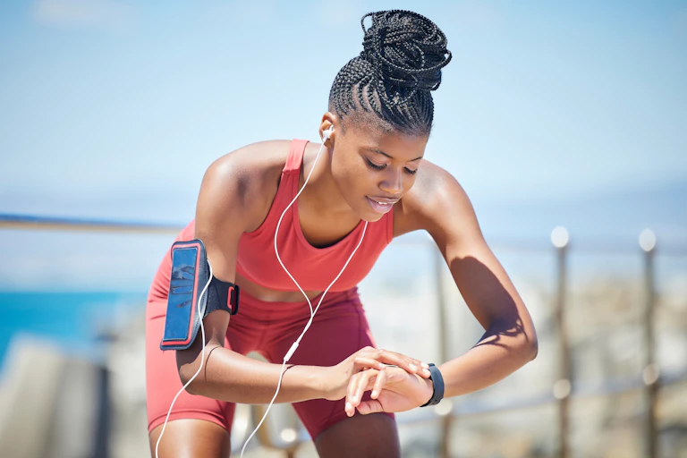 Woman by the sea doing exercise and running workout, while wearing a fitness tracker.