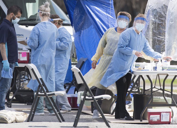 Health-care workers wearing personal protective equipment at a mobile COVID-19 test clinic in May 2020.