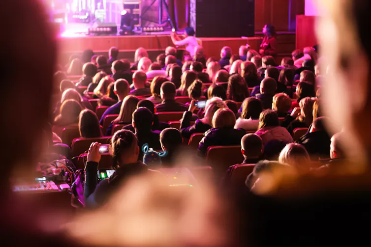 A crowd sits in rows in a concert hall.