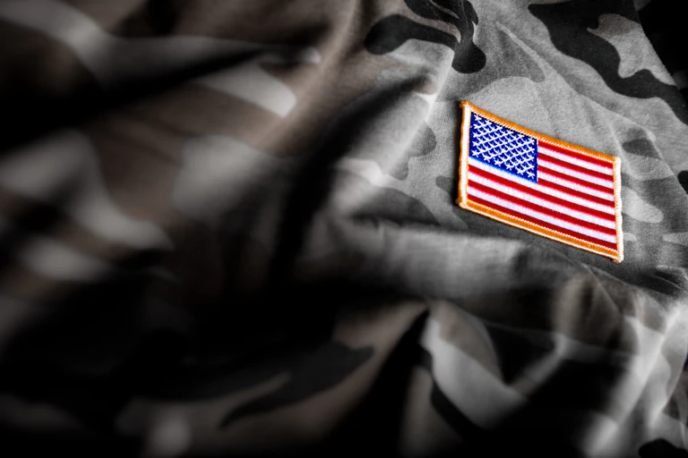 American flag patch on a black and gray camouflage uniform.
