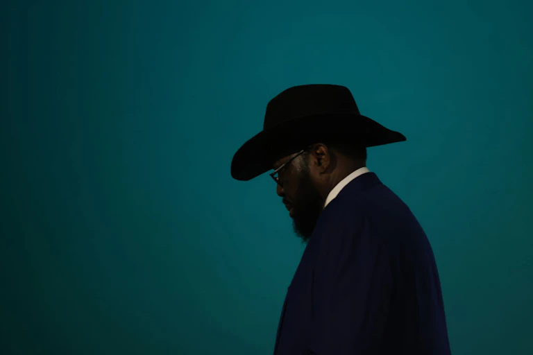 Profile of a man wearing a dark hat, with spectacles and a beard