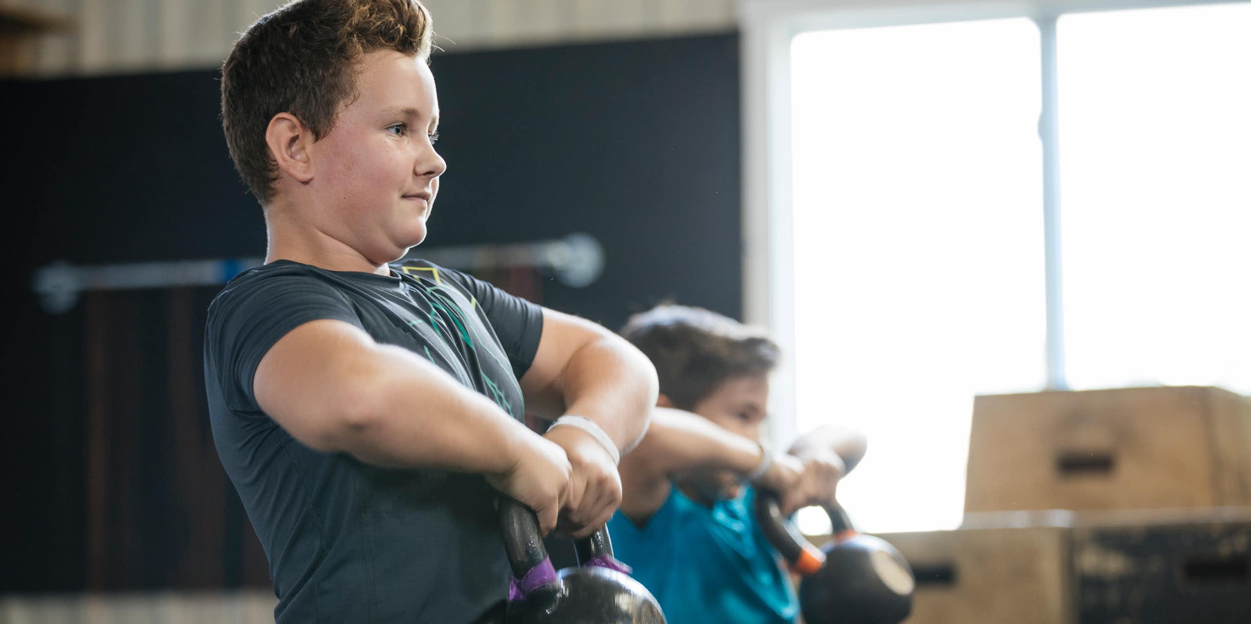 Two boys lifting kettlebells.
