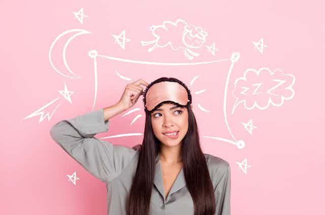Young woman wearing sleep mask with doodles around her head