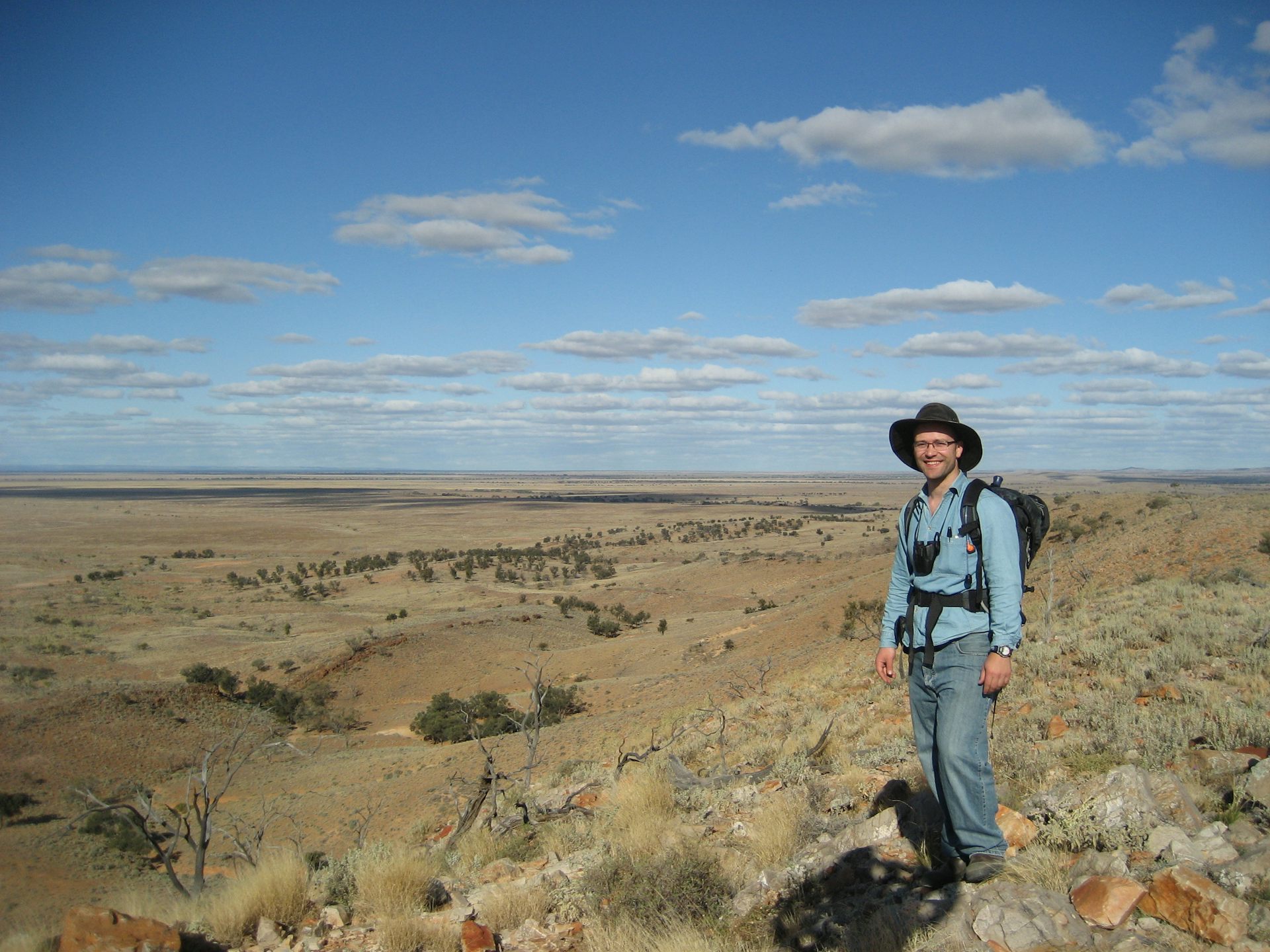 Man wearing hat standing in front of landscape.