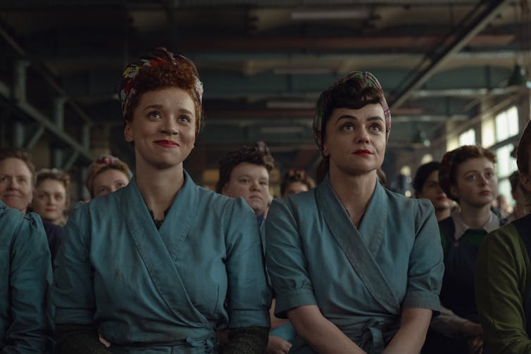 Two young women during the second-world war, dressed in overalls in a munitions factory.