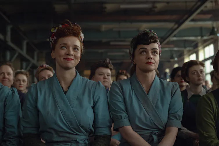 Two young women during the second-world war, dressed in overalls in a munitions factory.