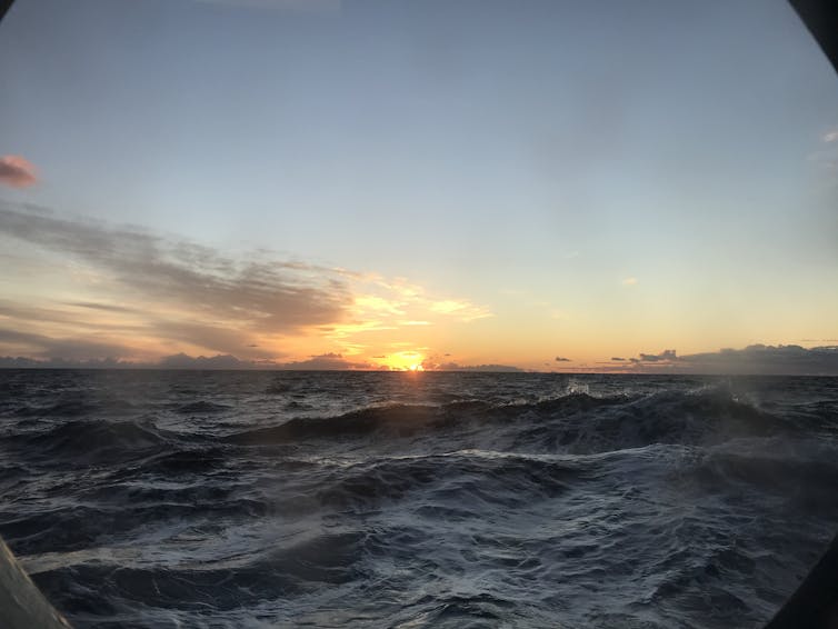 view of wavy ocean, sunrise on horizon
