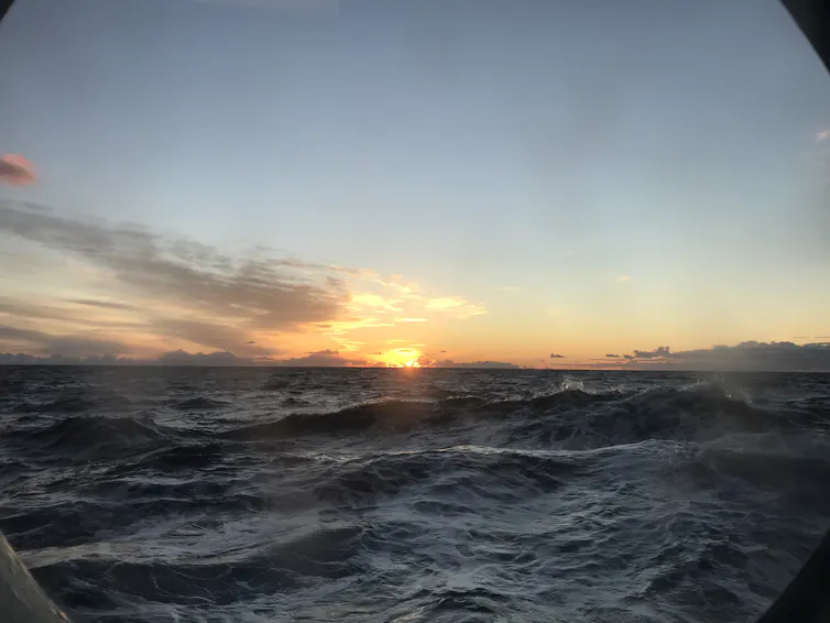 view of wavy ocean, sunrise on horizon