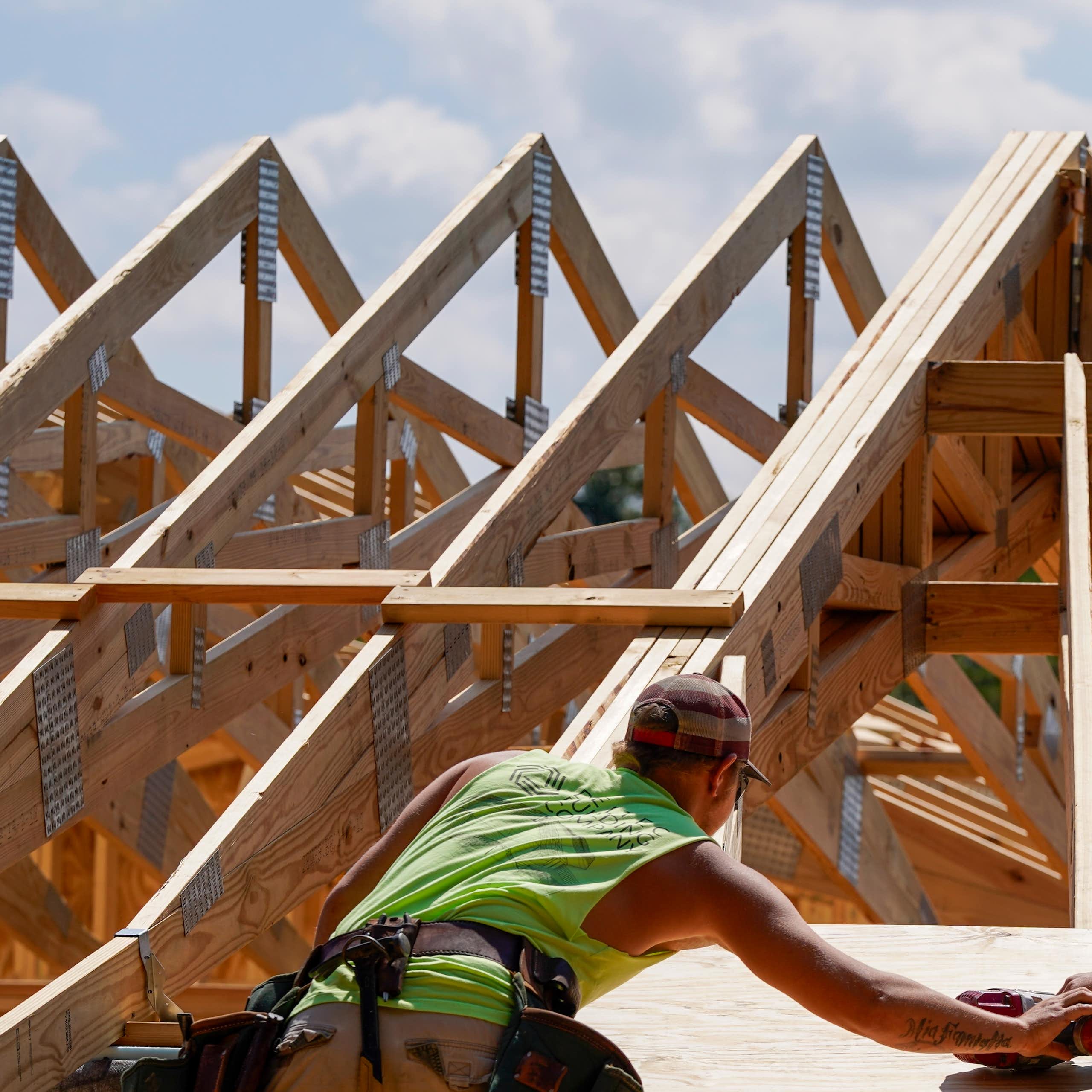 Two construction workers work on the roof of a home. It has a curve design to stand up to wind.