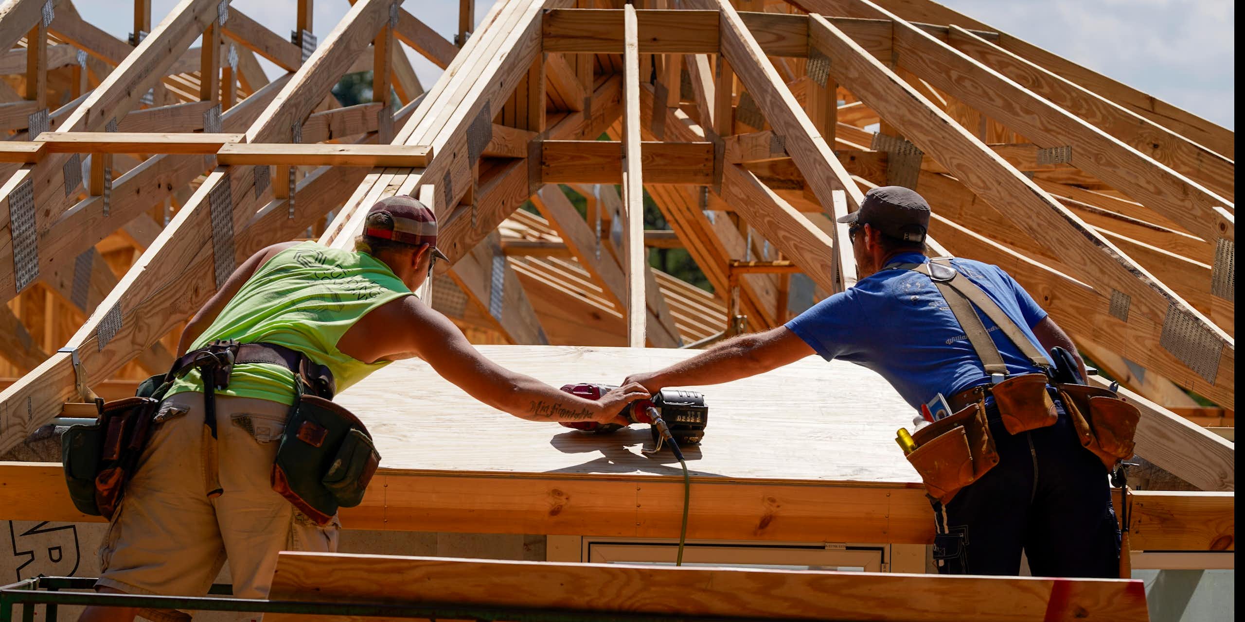 Two construction workers work on the roof of a home. It has a curve design to stand up to wind.