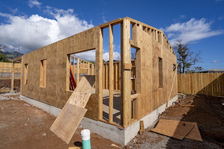 The first story of a home under constructions. Walls are going up, but the roof is still open to the blue sky.