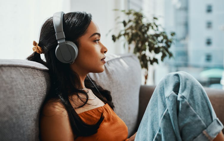 Person wearing headphones listening to music while sitting on couch