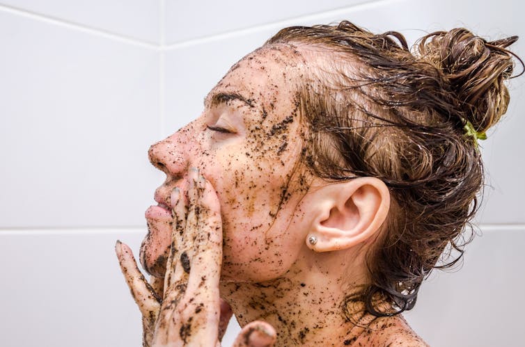 A woman uses a facial scrub.