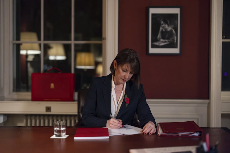 Rachel Reeves sits at her desk and signs a document