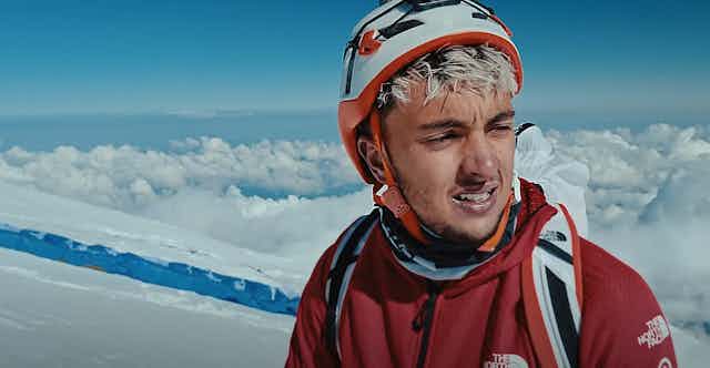 Un homme en tenue d'alpinisme se trouve en haute altitude.