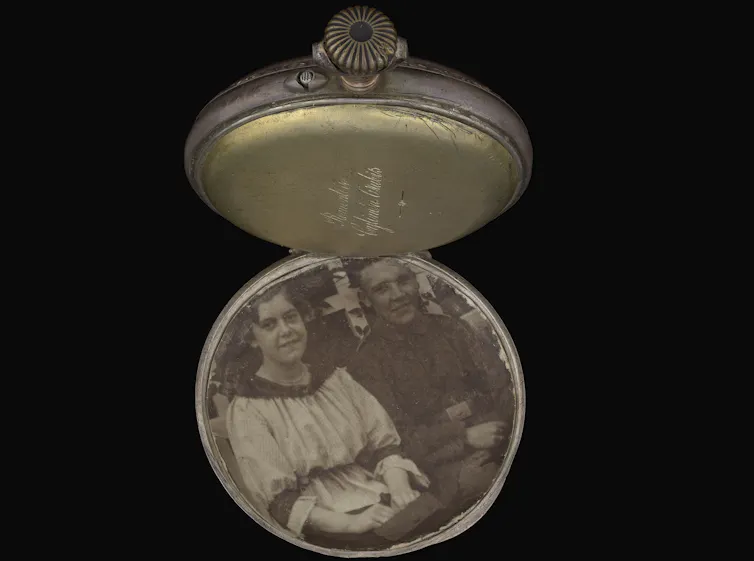 An open pocket watch showing a black-and-white photograph of a young German couple.