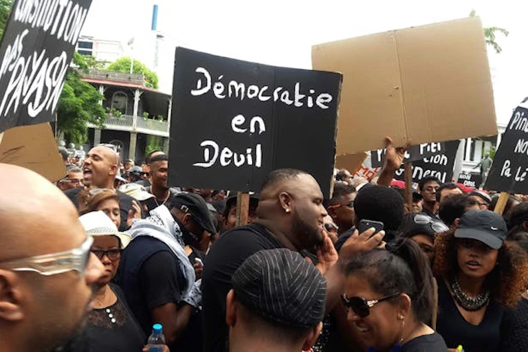 Des manifestants tiennent une pancarte sur laquelle on peut lire « Démocratie en détresse ».