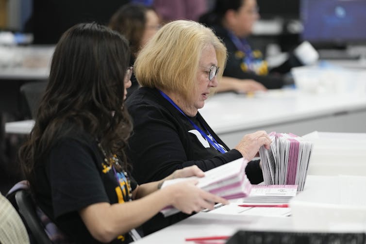 Two women hold ballots.