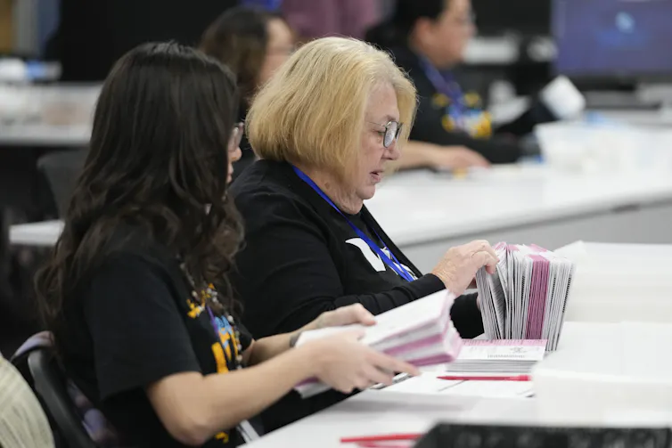 Two women hold ballots.