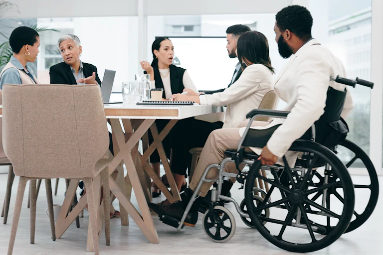 Une réunion de travail, avec une personne dans un fauteuil roulant.